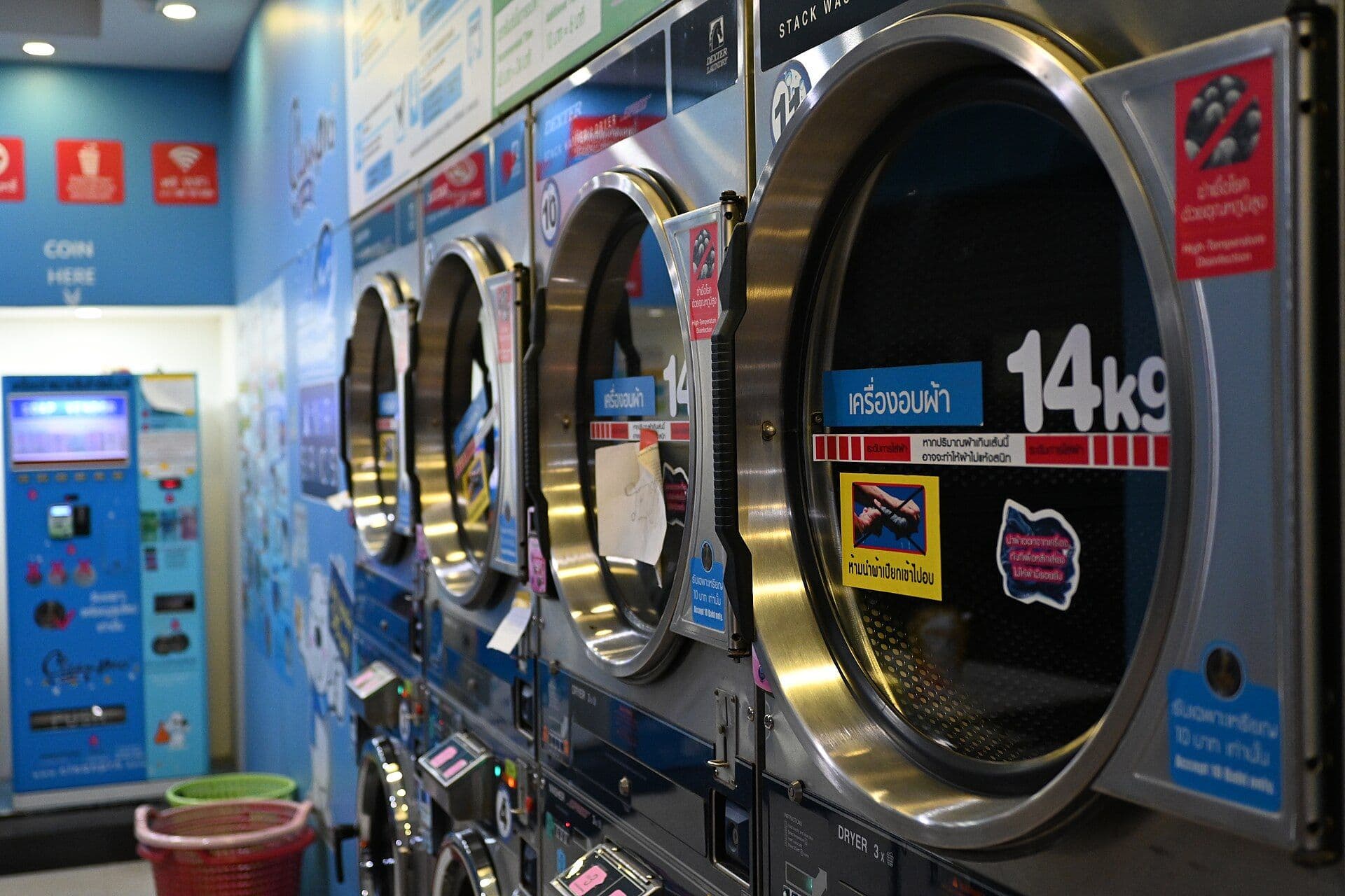 Row of industrial front-loading washing machines with large circular glass doors in a laundromat