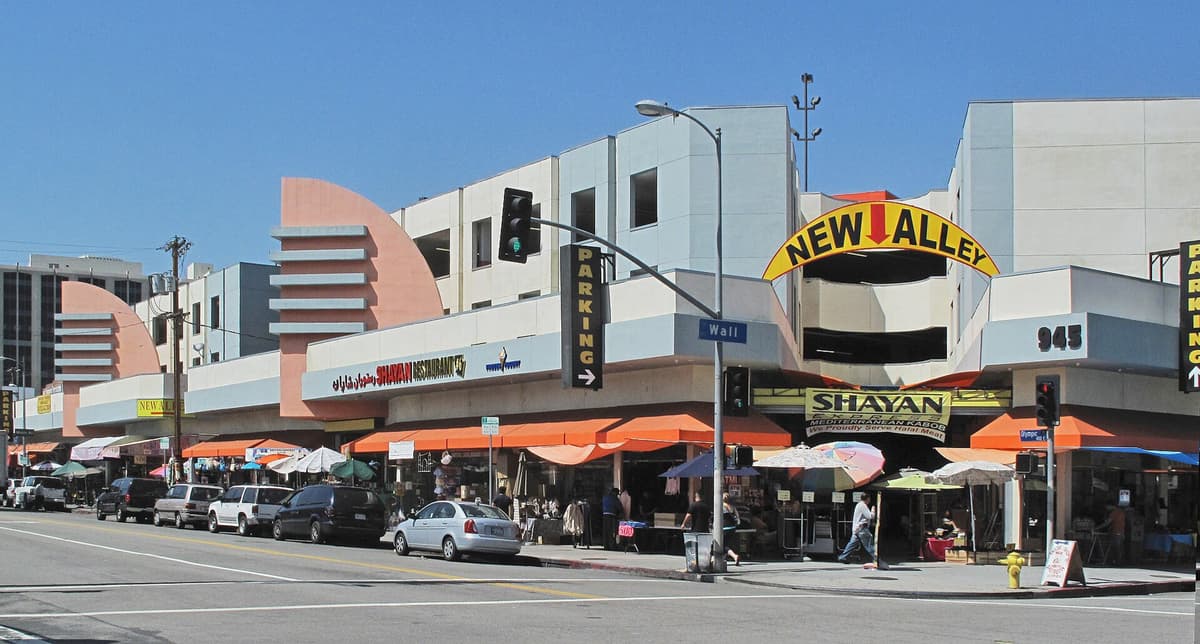 Concrete building with a parking structure, orange awnings and storefronts on a street corner in a city fashion district