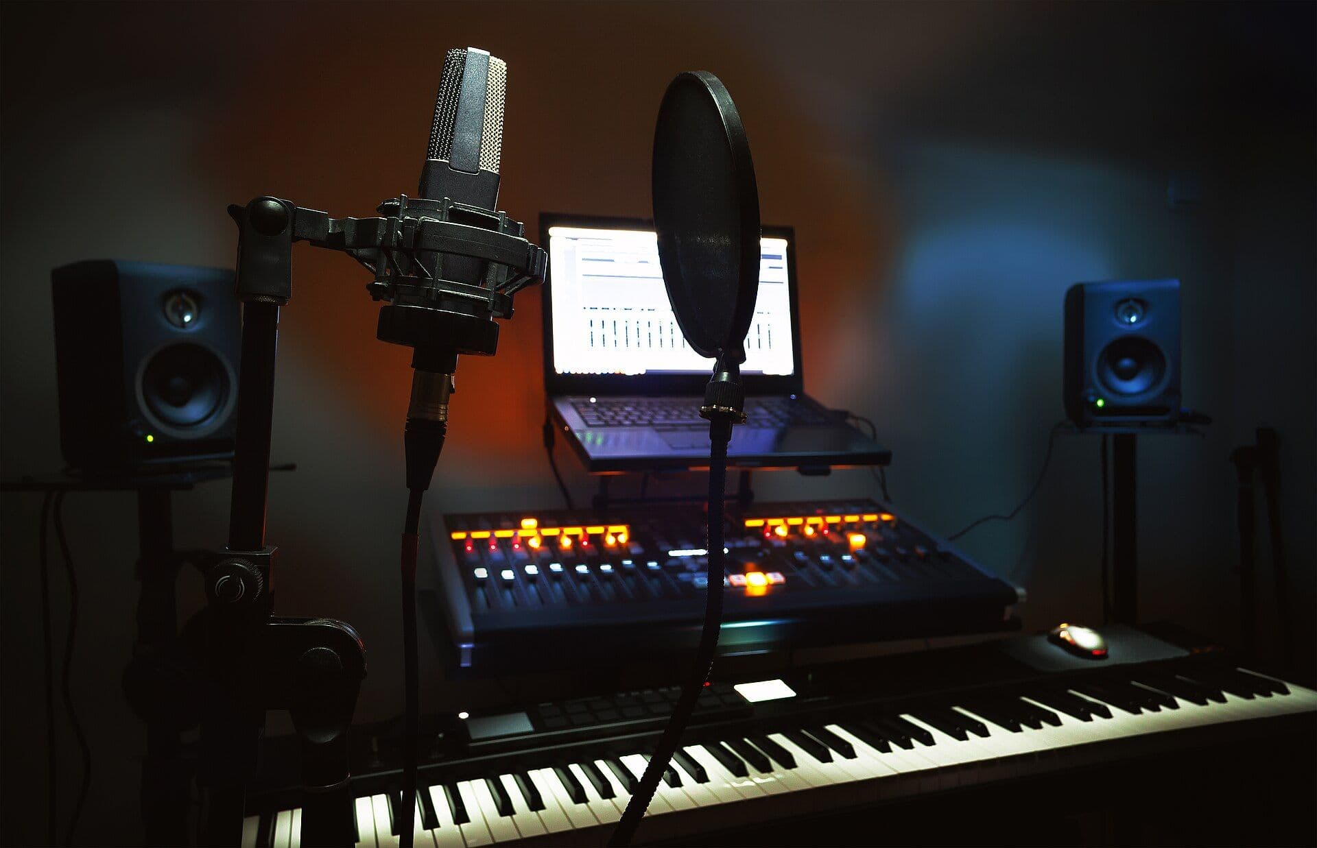 Recording studio equipment including microphone, mixing console, laptop with DAW software, and studio monitors