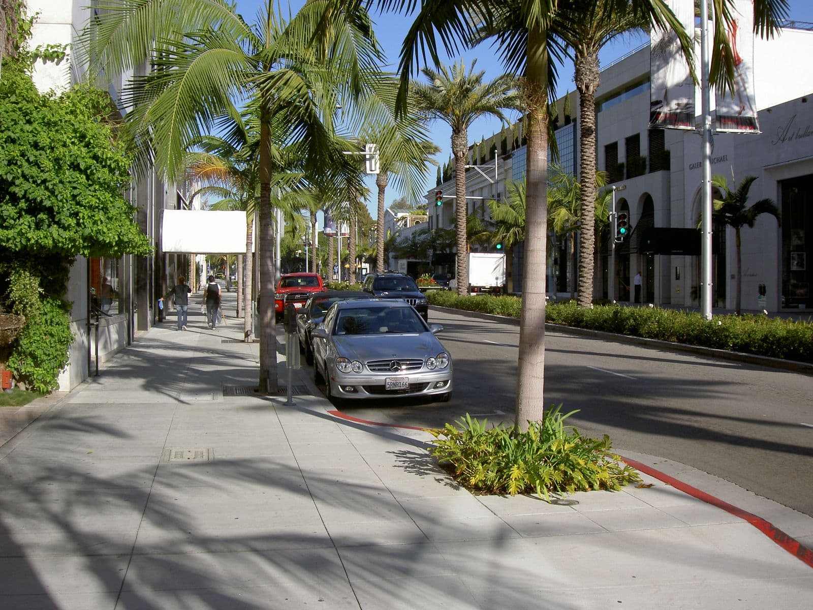 Rodeo Drive street view with palm trees, shops, and parked cars under blue sky