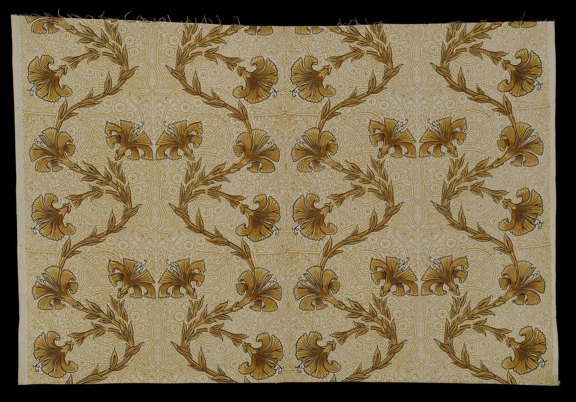 Historic textile sample with repeating gold botanical motifs on cream background