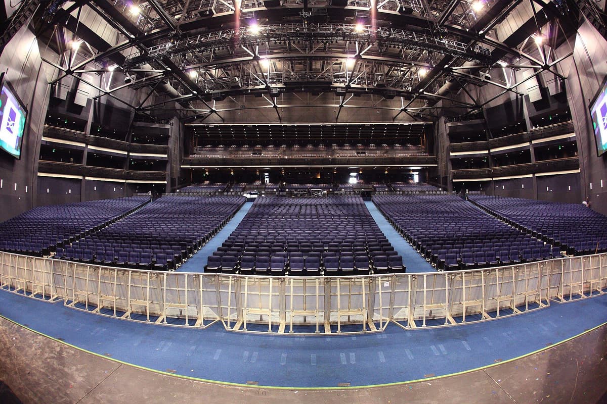 Interior view of an empty theater auditorium with blue seating and overhead lighting infrastructure
