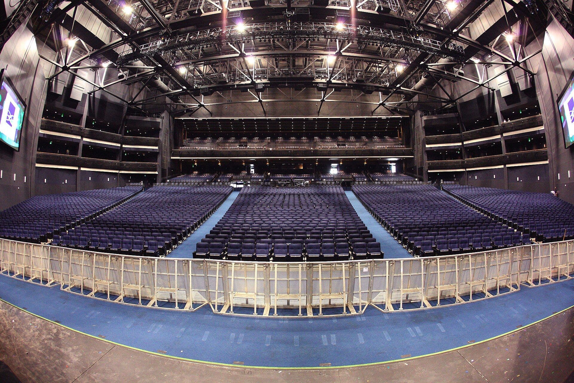 Interior view of an empty theater auditorium with blue seating and overhead lighting infrastructure