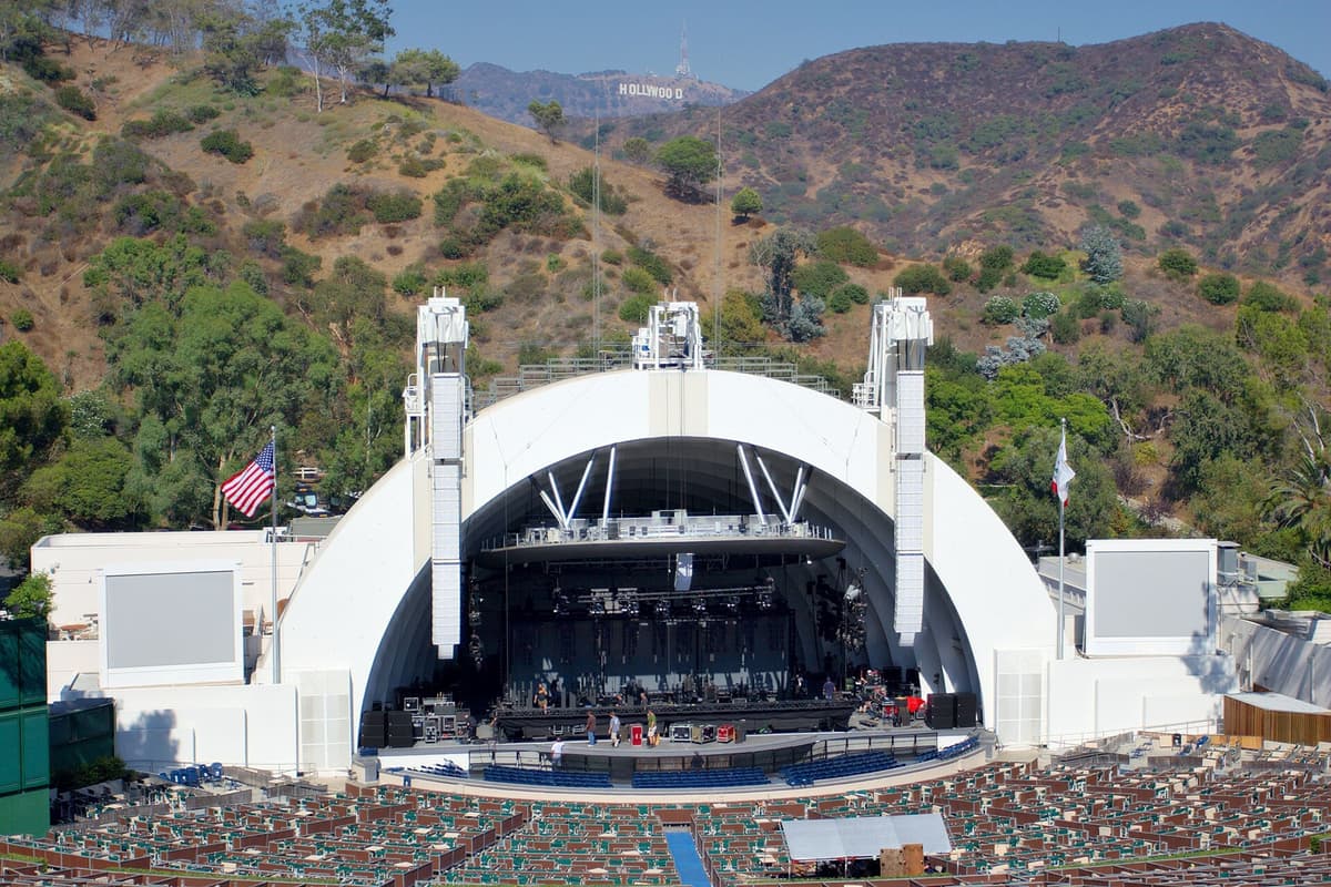 Hollywood Bowl amphitheatre with its white shell stage and empty seats, with the Hollywood sign on the hills behind