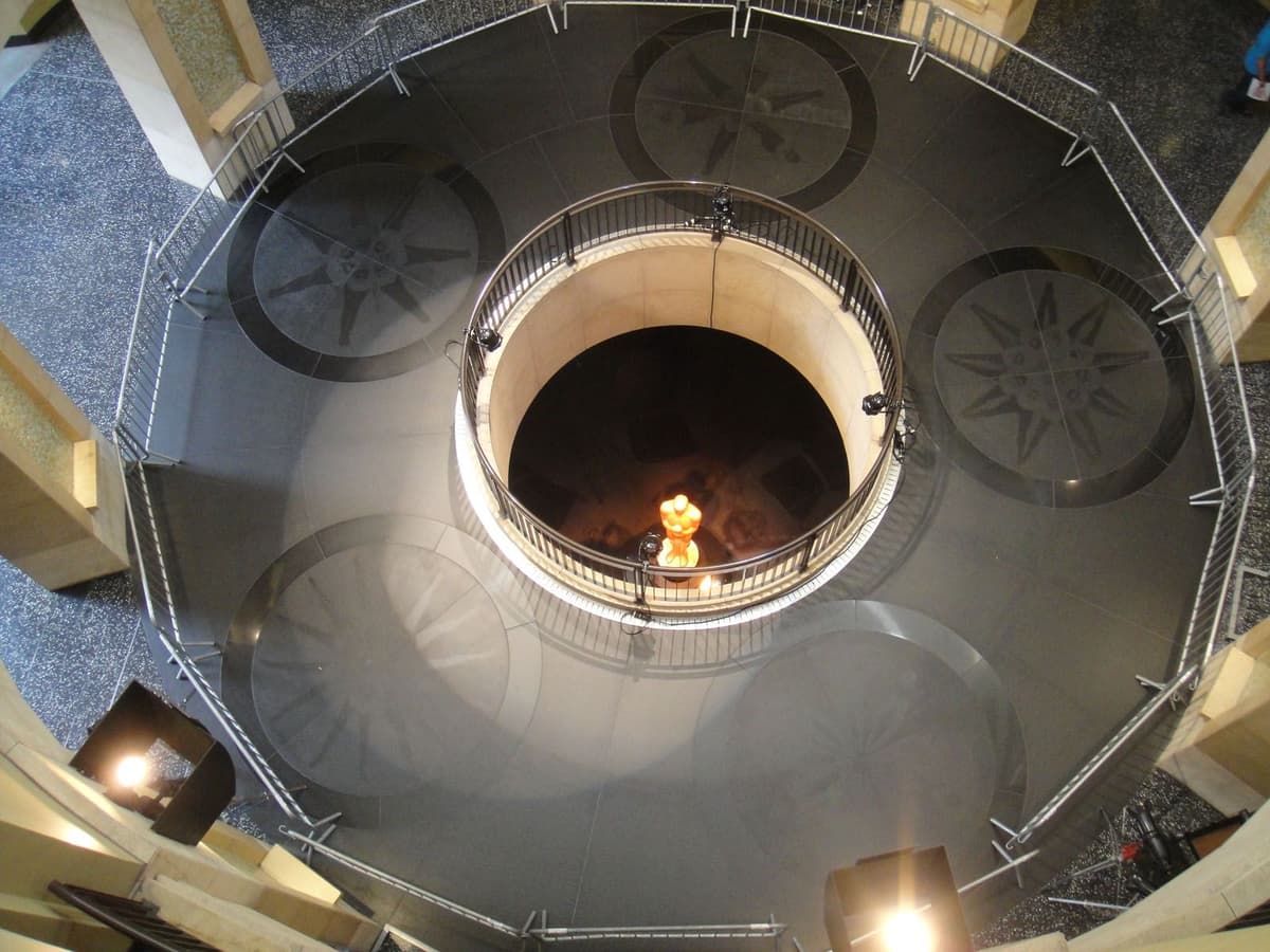Aerial view of an Oscar statuette lit at the bottom of a circular, tiered atrium with a railing