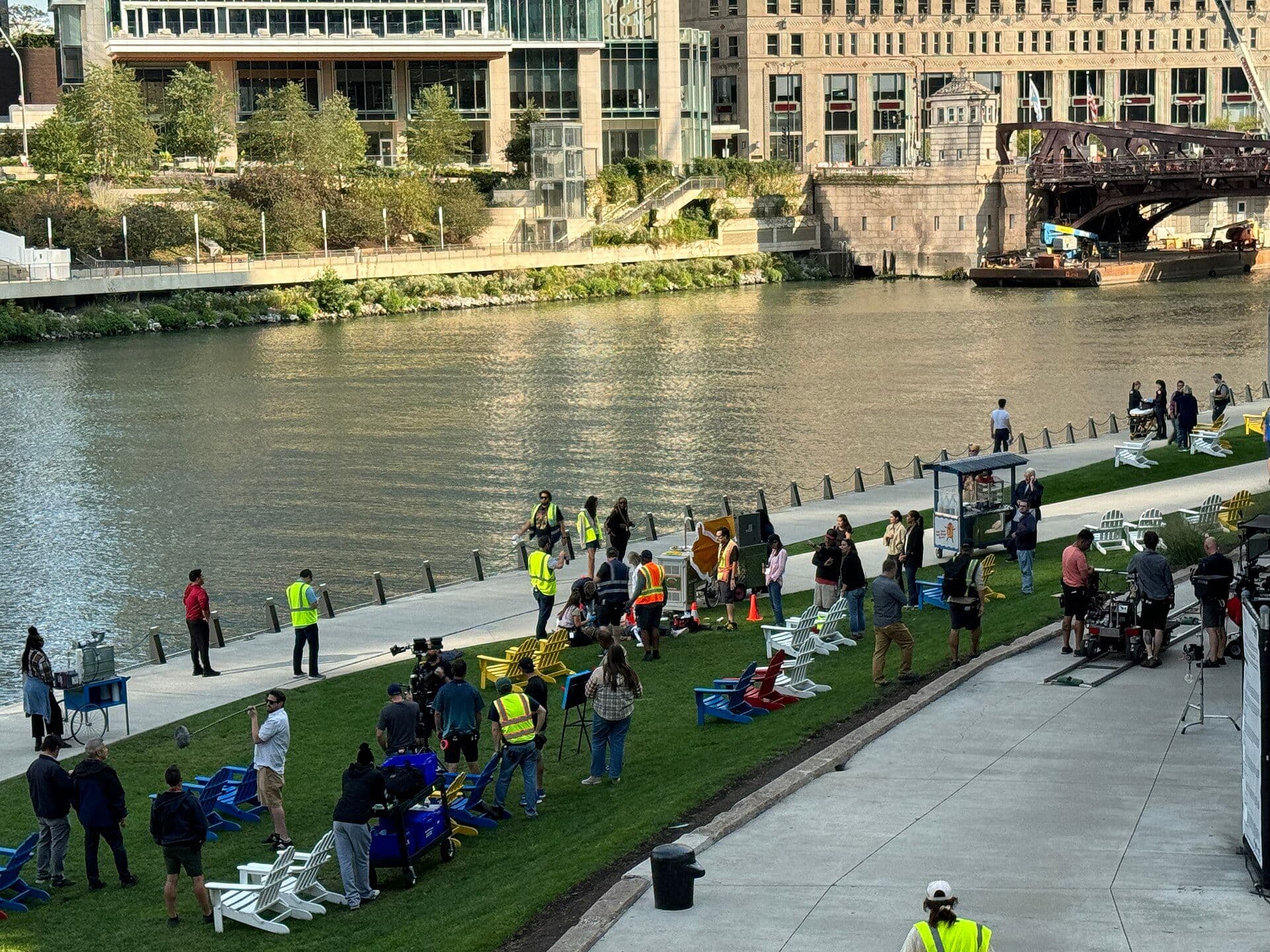 Film production crew and equipment during a television shoot on a riverwalk