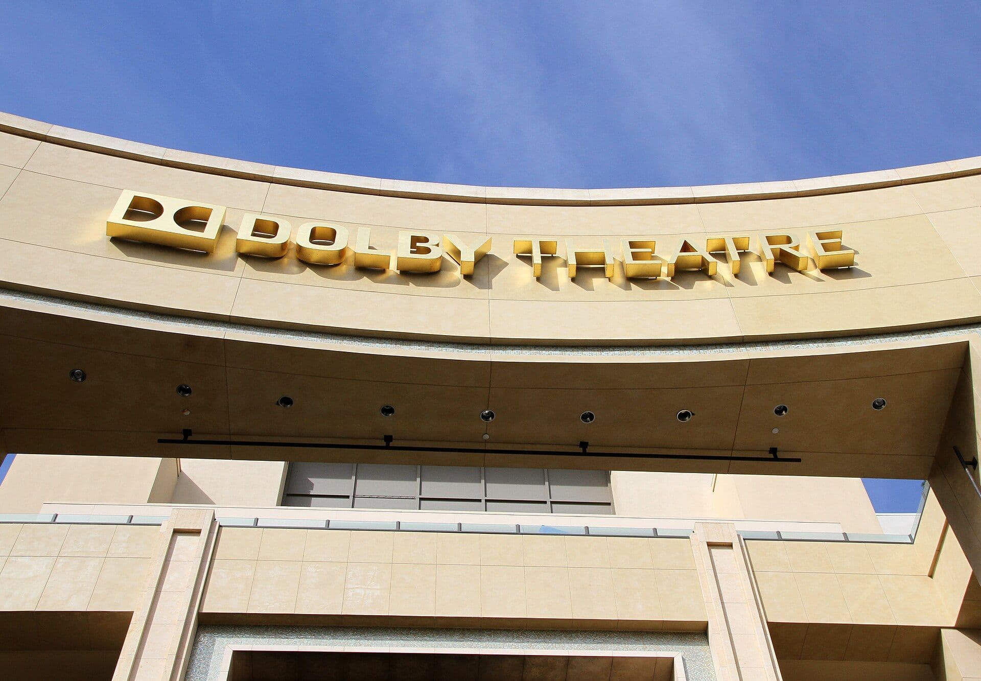 Exterior of the Dolby Theatre with gold signage and architectural details against blue sky