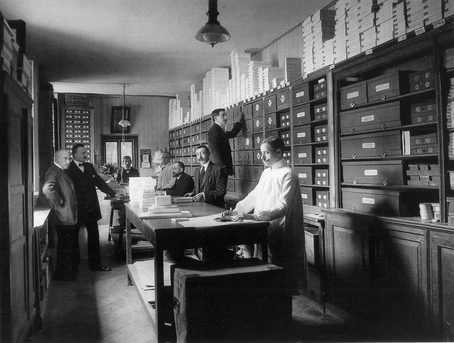 Interior of a luxury fashion house with workers organizing merchandise in numbered storage units