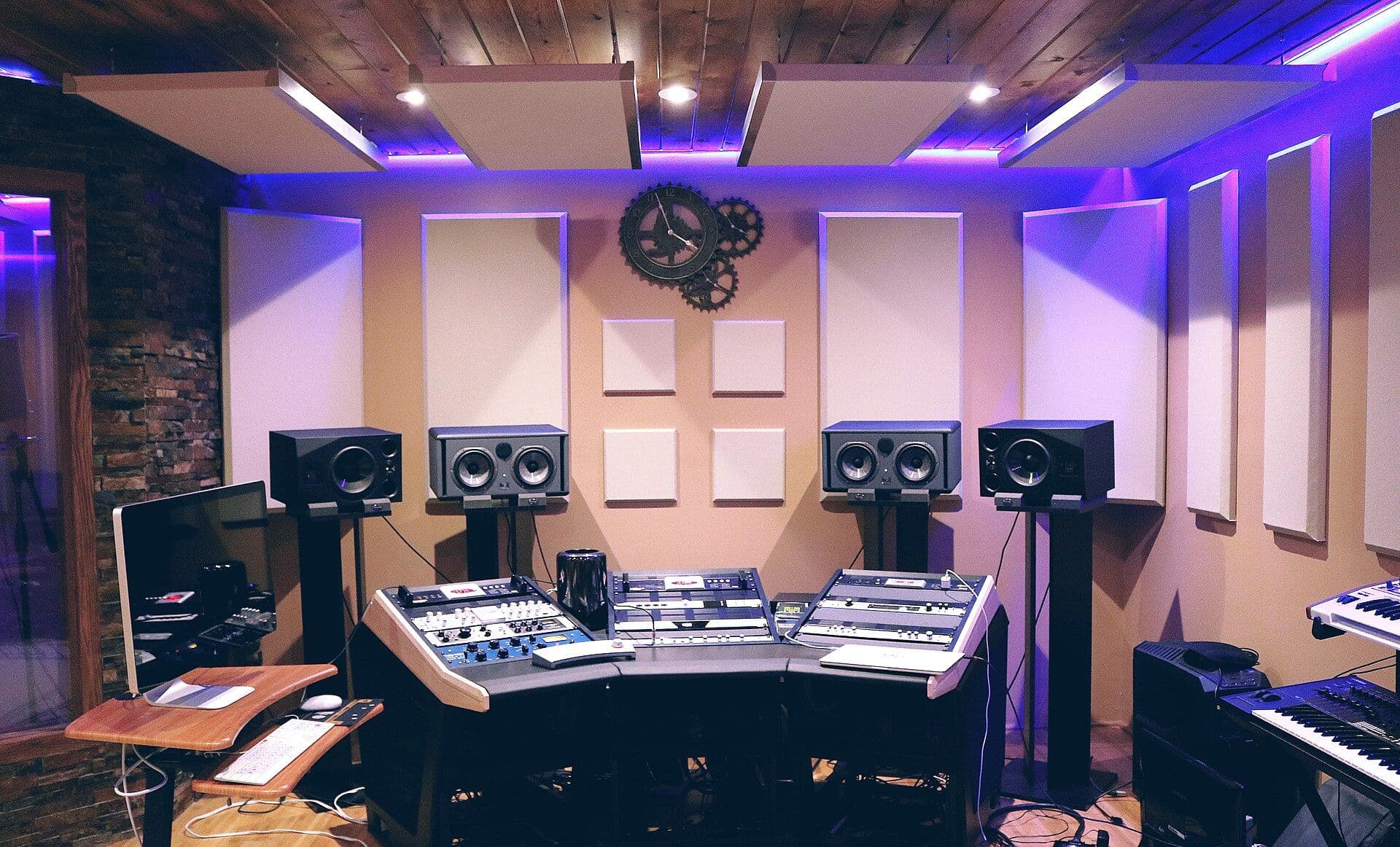 Recording studio control room with mixing console, DAW displays, and speakers