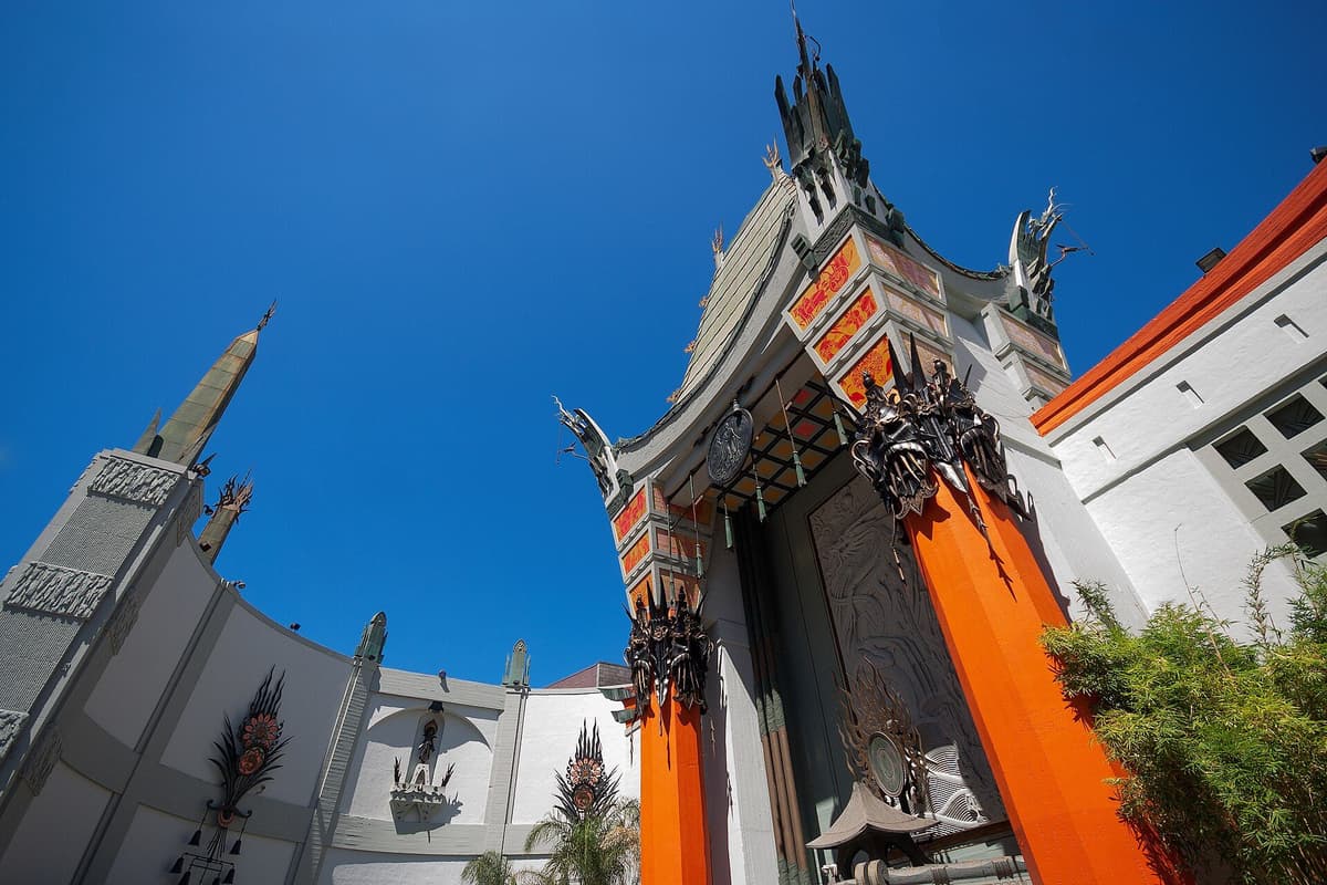 Ornate pagoda-style theatre facade with orange columns and carved details, seen from below against a deep blue sky