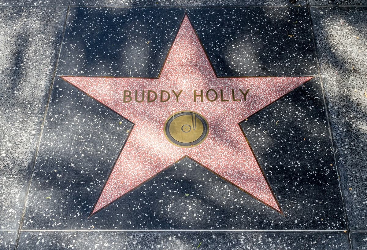 Pink terrazzo star reading BUDDY HOLLY with a brass record emblem, set in a dark speckled pavement