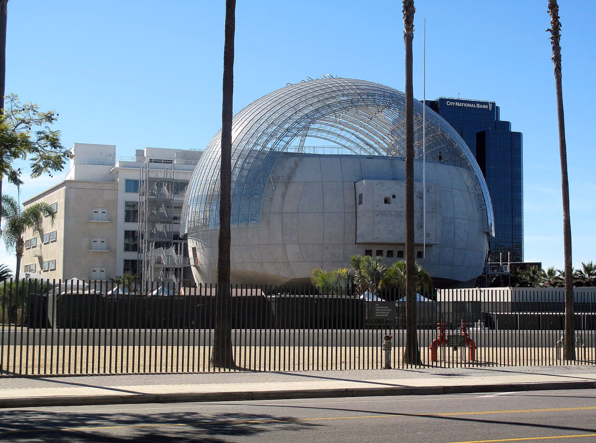 The spherical glass and metal Sphere building of the Academy Museum of Motion Pictures against a blue sky.